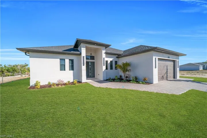 Prairie-style home with a front lawn, stucco siding, and a garage