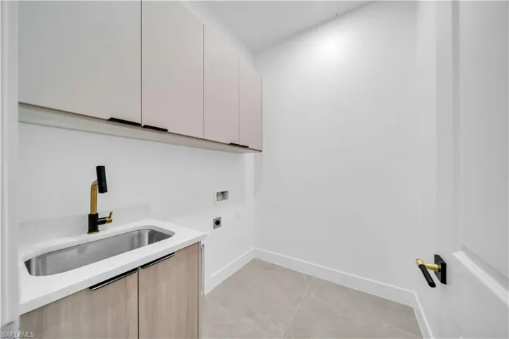 Laundry room with cabinet space, light tile patterned floors, hookup for an electric dryer, and hookup for a washing machine