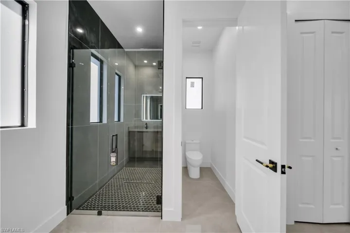 Bathroom with a shower stall, light tile patterned flooring, recessed lighting, and healthy amount of natural light