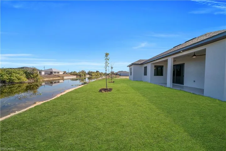 View of green lawn featuring a patio area, a water view, a ceiling fan, and a residential view