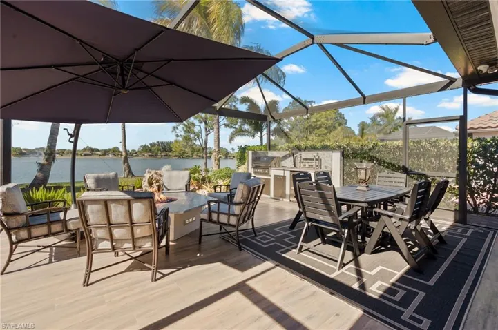 Deck featuring an outdoor fire pit, glass enclosure, outdoor dining area, a water view, and a sunroom