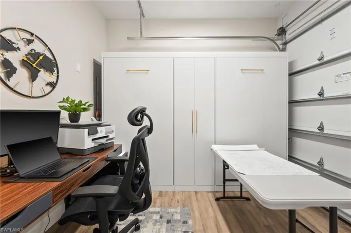Office area with light wood-style floors and a garage
