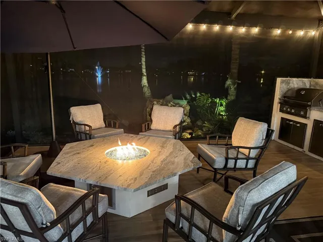Patio at night featuring a patio, an outdoor fire pit, and an outdoor kitchen