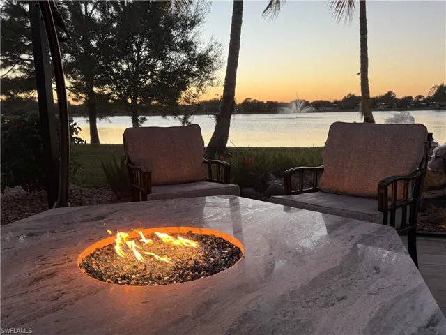Patio terrace at dusk featuring a water view and a fire pit