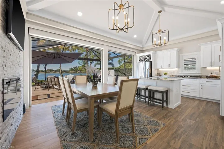 Dining space with dark wood-style flooring, beam ceiling, plenty of natural light, a chandelier, and a sunroom