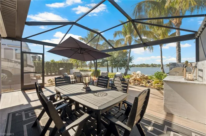 View of patio / terrace with glass enclosure, outdoor dining area, a sunroom, a water view, and exterior kitchen