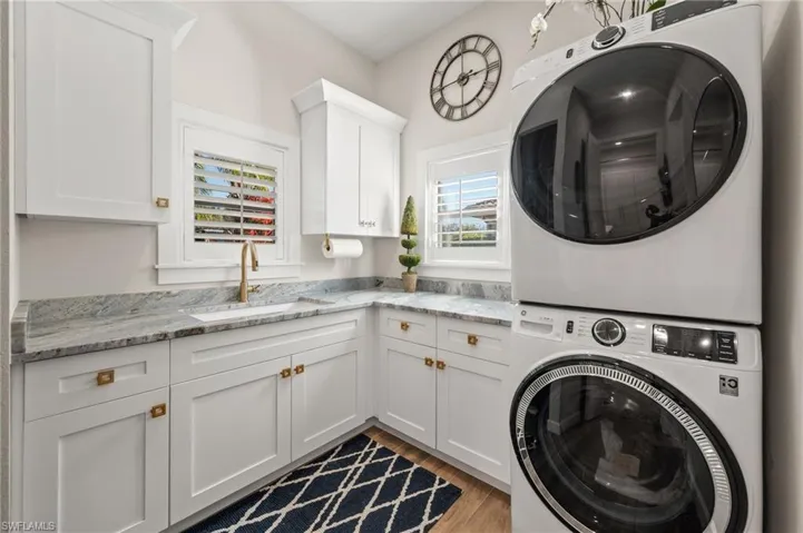 Washroom with estacked washer and dryer, cabinet space, and light wood-style floors