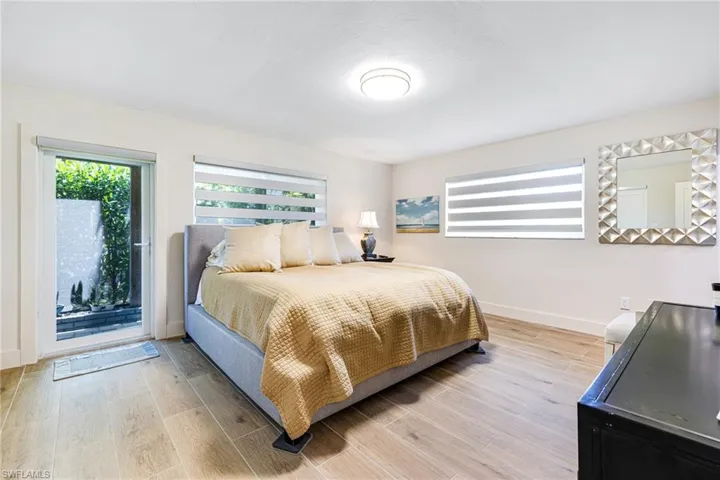 Bedroom featuring light wood-style flooring, baseboards, and access to exterior