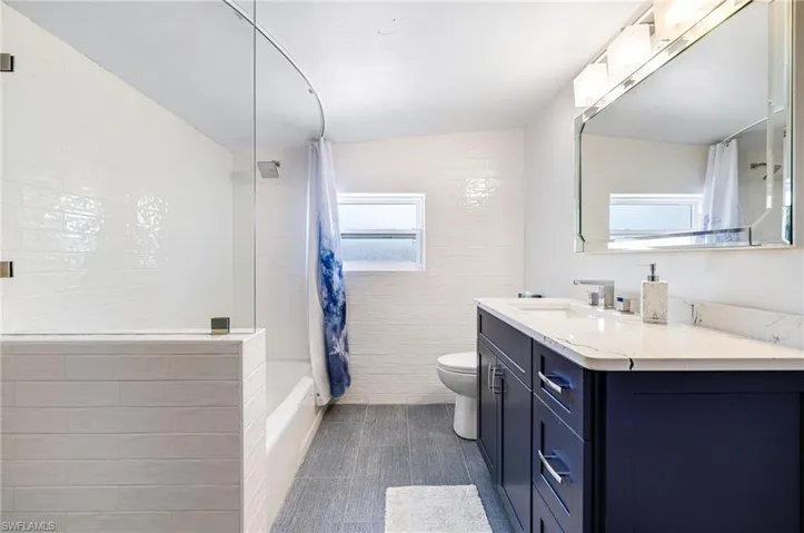 Full bath with shower / tub combo, vanity, tile patterned flooring, and toilet