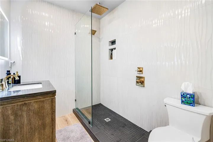 Full bathroom with tile walls, toilet, wood finished floors, and tiled shower