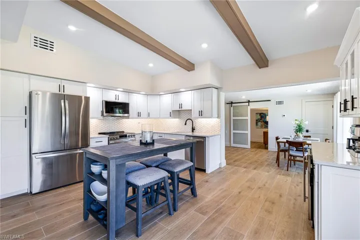 Kitchen featuring a barn door, visible vents, beam ceiling, tasteful backsplash, and appliances with stainless steel finishes