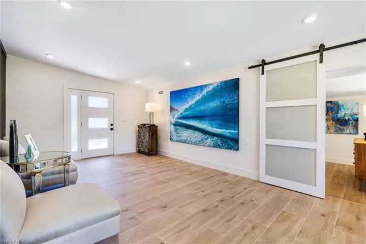 Living area featuring a barn door, light wood-style floors, baseboards, and recessed lighting