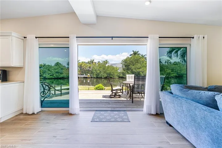 Doorway with lofted ceiling with beams, a wealth of natural light, wood tiled floor, and a water view