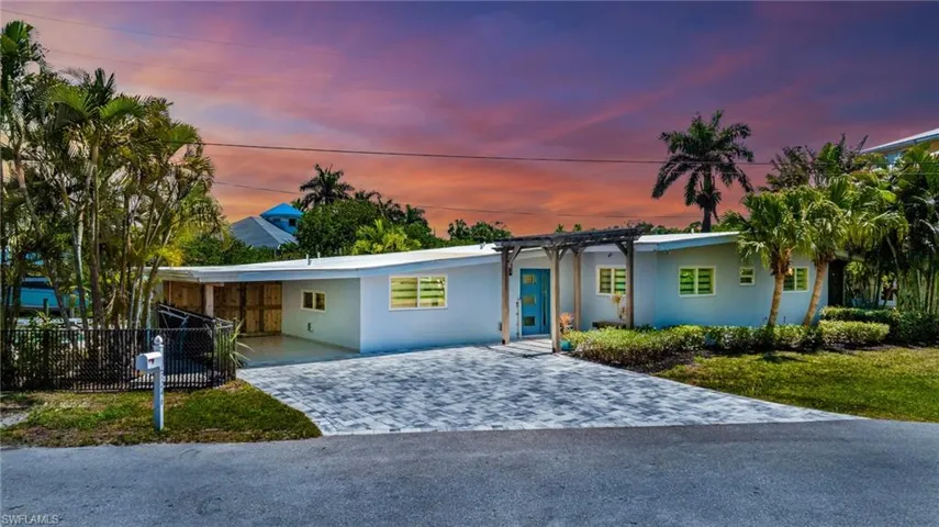 View of front of home with stucco siding, fence, a carport, and decorative driveway
