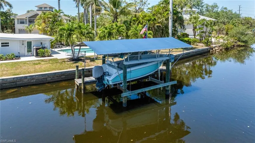 View of dock with an outdoor pool, boat lift, and a water view