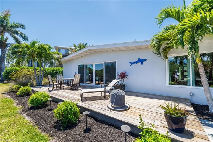 Back of house with a wooden deck, outdoor dining area, and stucco siding