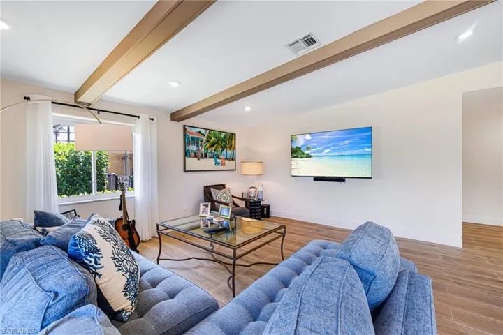 Living room with beamed ceiling, wood finished floors, baseboards, and recessed lighting