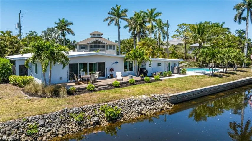 Rear view of property with stucco siding, a patio area, a water view, and a yard