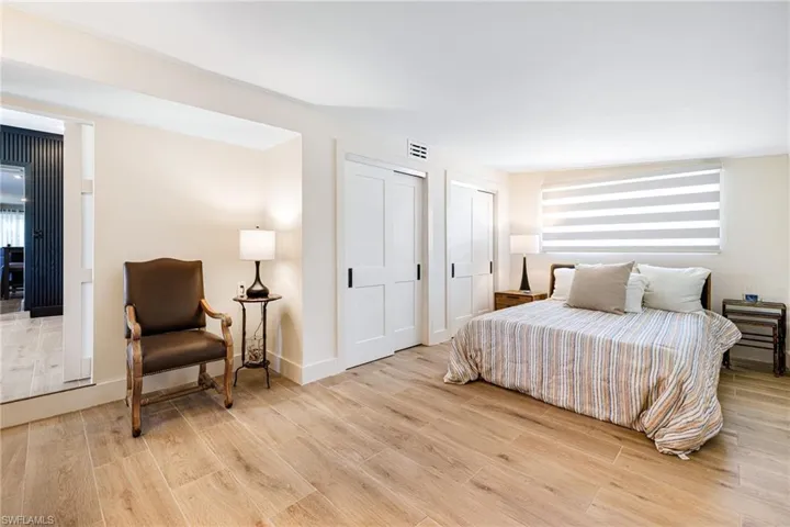 Bedroom featuring multiple closets, visible vents, light wood finished floors, and multiple windows