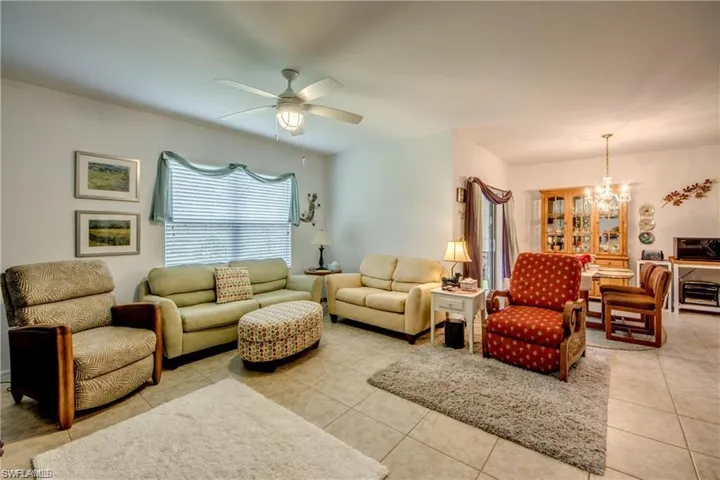 Living room with a chandelier, light tile patterned floors, and a ceiling fan