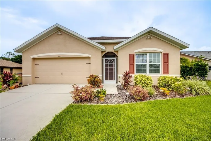 Ranch-style house with stucco siding, an attached garage, concrete driveway, and a front yard
