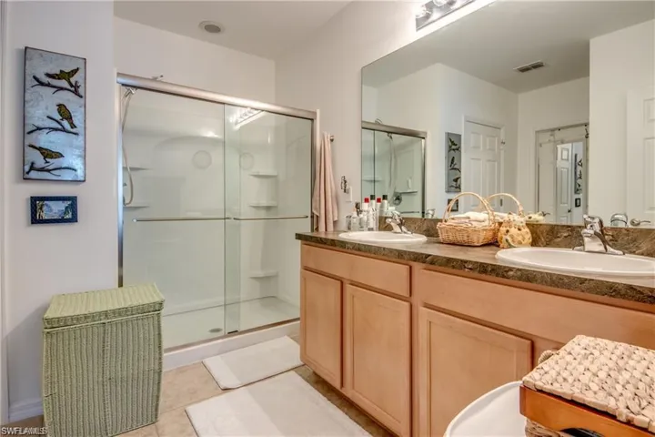 Full bath with a stall shower, tile patterned flooring, and double vanity