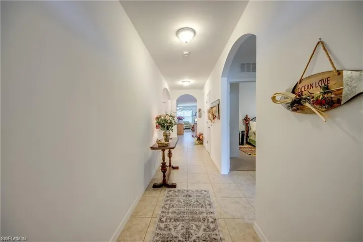 Hallway with arched walkways and light tile patterned floors