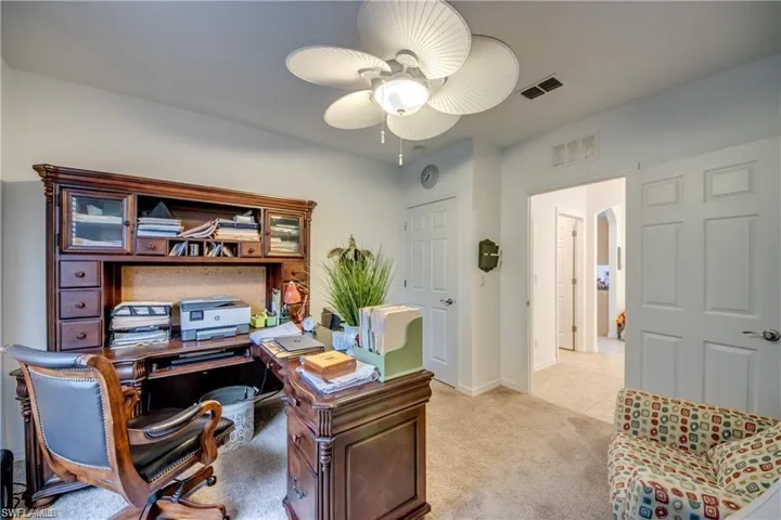 Office space featuring a ceiling fan, light carpet, and baseboards