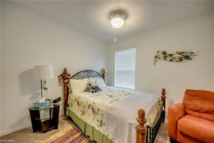 Bedroom with light colored carpet, baseboards, and ceiling fan