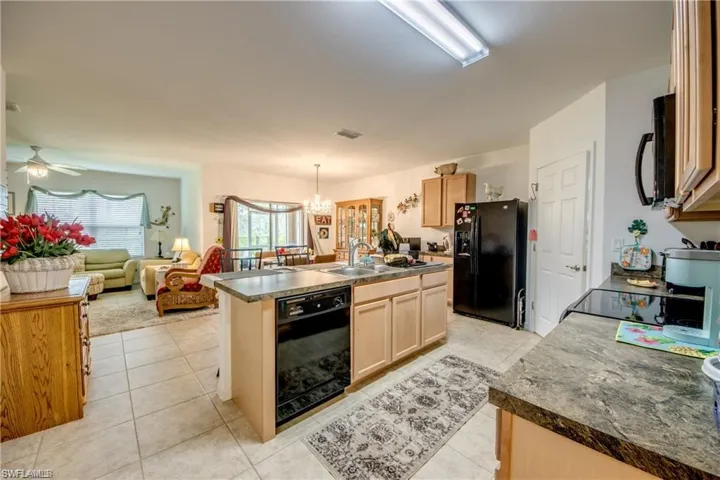 Kitchen featuring black appliances, a sink, a kitchen island with sink, a chandelier, and open floor plan