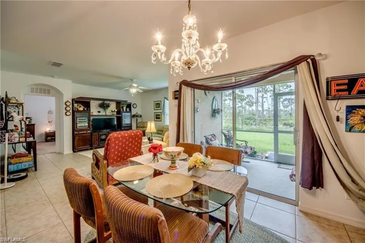 Dining space with light tile patterned floors, arched walkways, ceiling fan, a chandelier, and baseboards