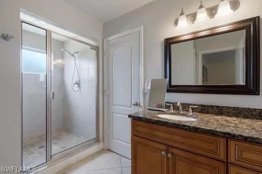 Bathroom featuring vanity, light tile patterned floors, and a shower stall