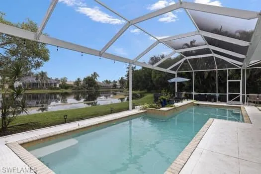 Outdoor pool with a lanai, a sunroom, a water view, and a patio