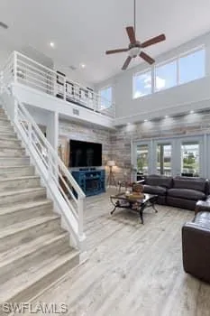 Living room with a towering ceiling, light wood-style floors, and a ceiling fan