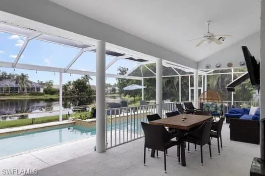 Sunroom / solarium featuring vaulted ceiling, a patio area, ceiling fan, and a water view