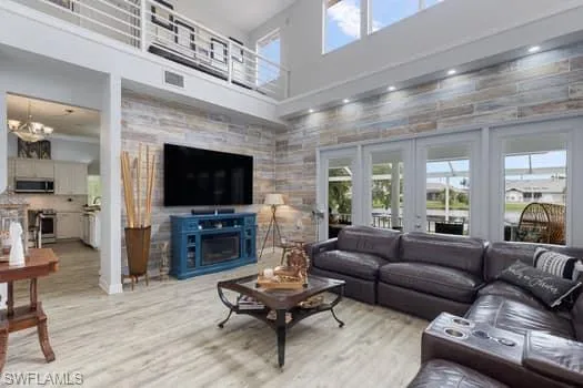 Living room with a towering ceiling, wood finished floors, a fireplace, and a chandelier