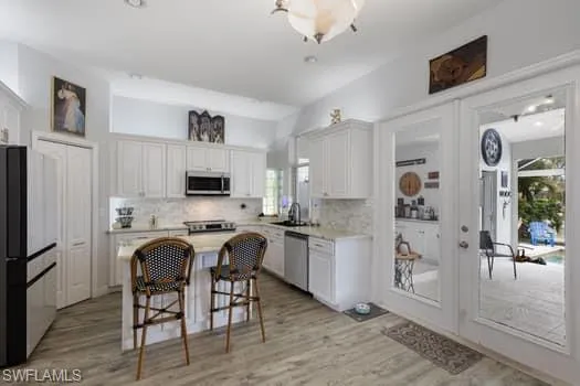 Kitchen featuring appliances with stainless steel finishes, light wood-type flooring, and white cabinets