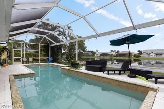 Swimming pool featuring glass enclosure, a patio, and a sunroom