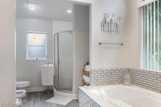 Bathroom featuring a garden tub, a stall shower, light wood-type flooring, and a bidet