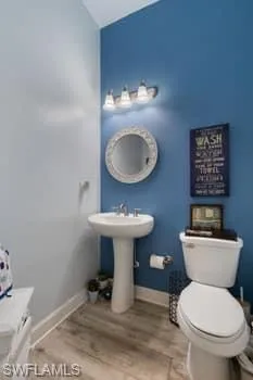 Half bath with light wood finished floors and lofted ceiling