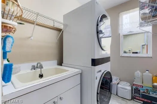 Washroom featuring stacked washer / dryer and a sink