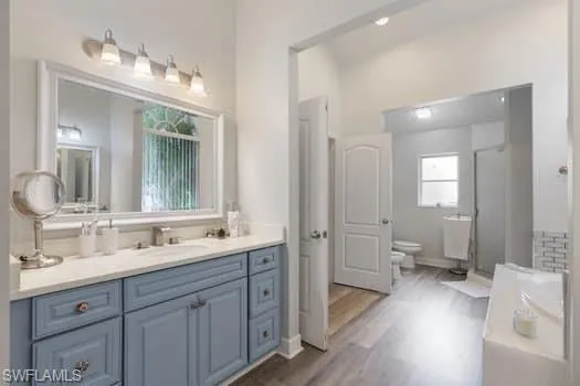 Bathroom featuring vanity, dark wood-style floors, a bath, and a stall shower