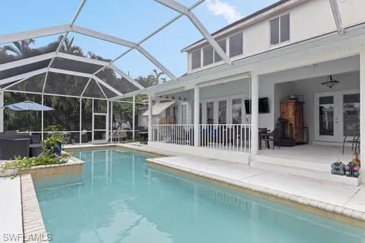 Swimming pool featuring french doors, a patio area, a sunroom, and glass enclosure
