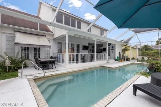 Back of house featuring a sunroom, a patio, an outdoor pool, and a lanai