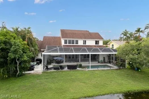 Rear view of house featuring a sunroom, a lawn, a patio, and a lanai