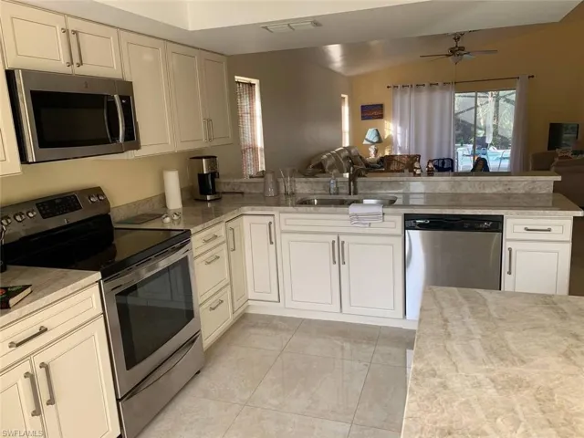 Kitchen featuring open floor plan, a sink, a ceiling fan, a peninsula, and appliances with stainless steel finishes