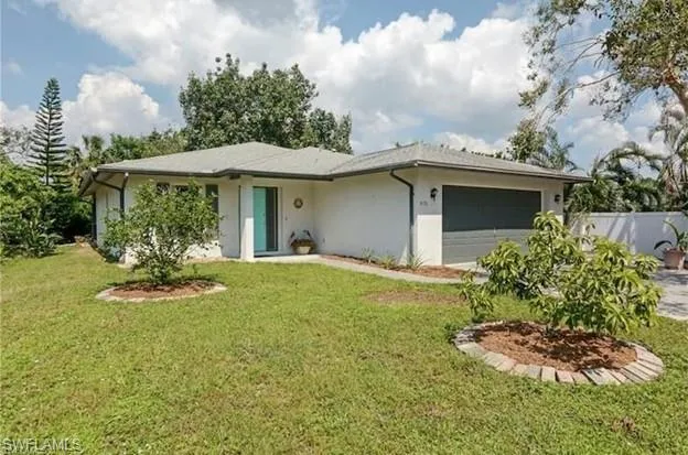 Ranch-style house with stucco siding, an attached garage, fence, and a front lawn