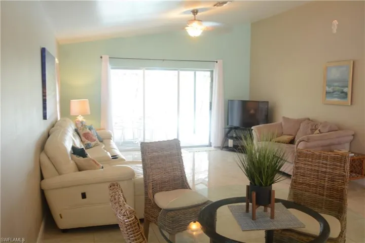 Living area featuring ceiling fan, vaulted ceiling, and light tile patterned floors