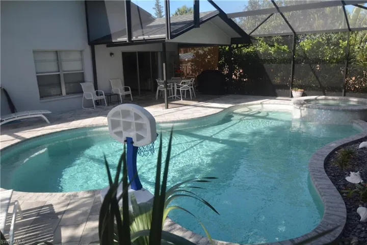 View of pool with a patio, a pool with connected hot tub, and glass enclosure