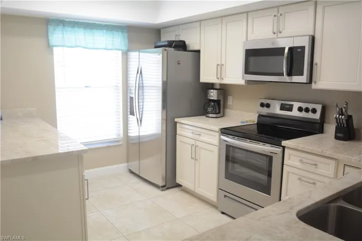 Kitchen featuring a sink, a wealth of natural light, light tile patterned flooring, and stainless steel appliances